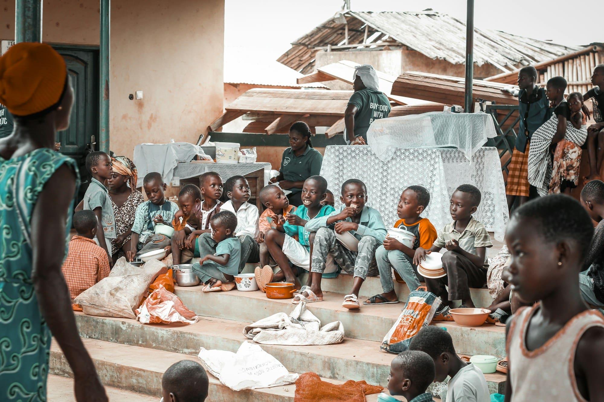 Children sit together on steps sharing a meal