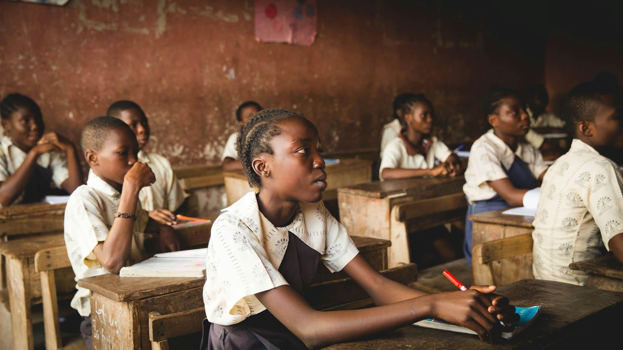Pupils in school uniform seated at wooden desks in a classroom in Lagos