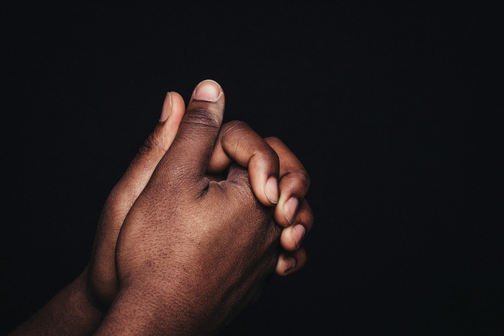 Two hands clasped together against a dark background