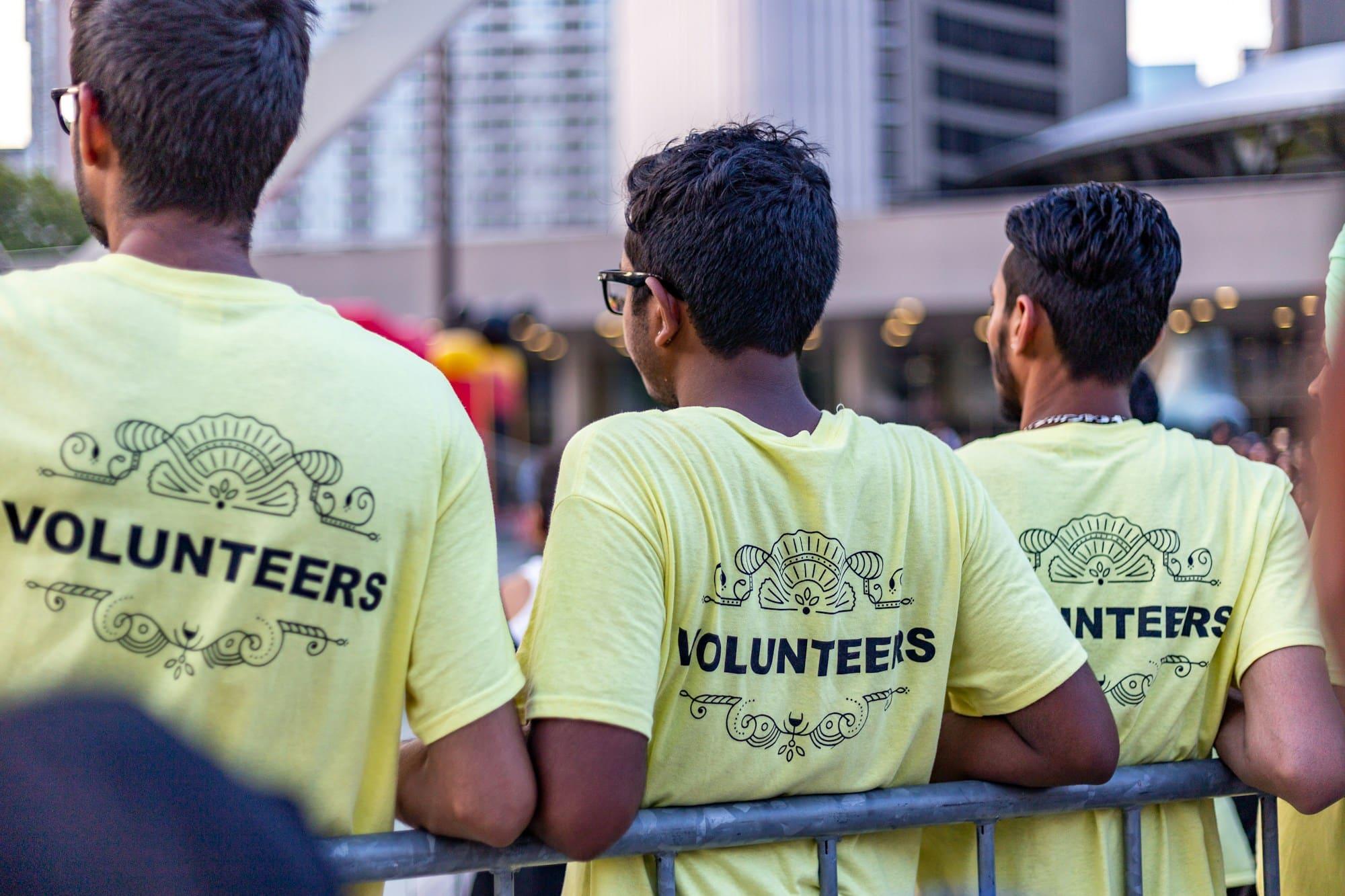 Three volunteers in matching yellow volunteer T-shirts, seen from behind